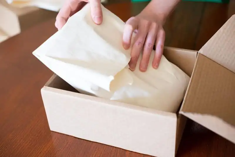 Hands packing a pair of shoes into a cardboard box for an order